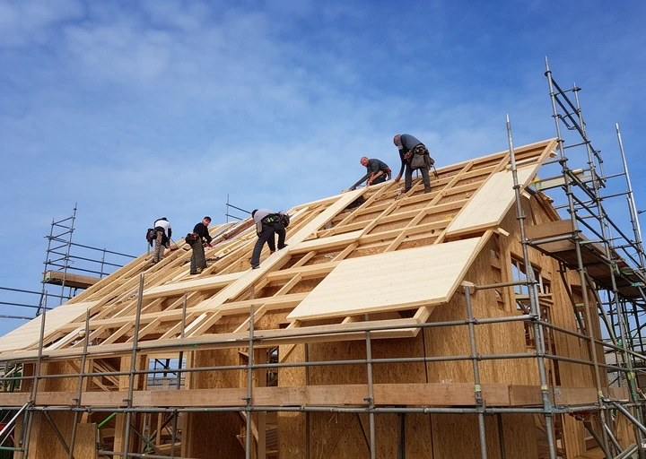 Crew fixing timber frame roof panels on a new house